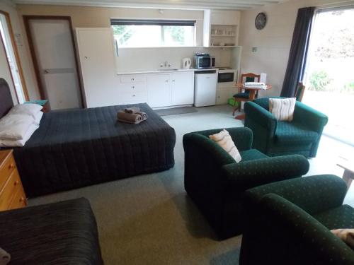 a living room with a bed and a couch and chairs at Rangiora Lodge Motel in Rangiora