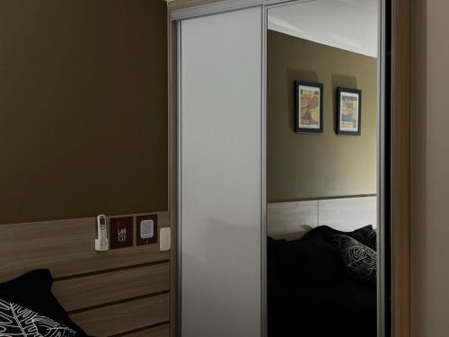 a large mirror in a bedroom with a bed at Flat com Ar, Piscina, Garagem, Cozinha e Wi-Fi in Campo Grande