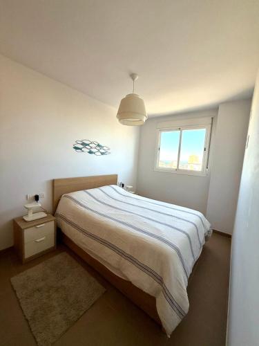 a bedroom with a large bed and a window at PRECIOSO APARTAMENTO PLAYA DE PILES in Piles