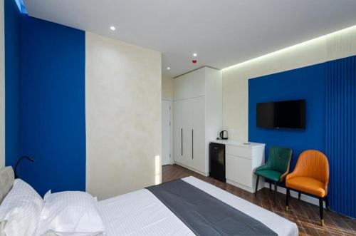 a bedroom with a blue wall with a bed and two chairs at Mashtots Avenue 31 in Yerevan