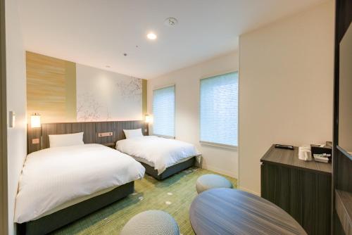 a hotel room with two beds and a desk at Miyako City Kintetsu Kyoto Station in Kyoto