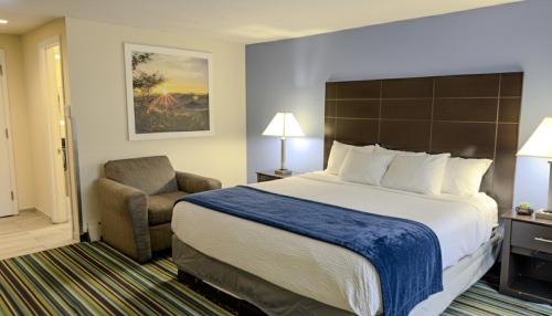 a hotel room with a large bed and a chair at Beacon Inn & Suites in Lincoln