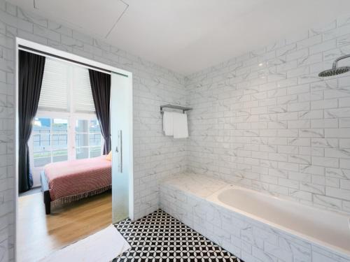 a white bathroom with a tub and a bed at The White House - Serviced Residences by Cove & Belle Living in Singapore