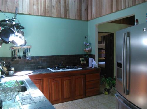 a kitchen with a stainless steel refrigerator and wooden cabinets at Rio Celeste Backpackers in Bijagua