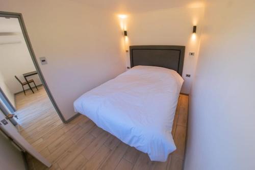 a small bedroom with a white bed and a mirror at Cabaña El Quillay in Santa Cruz