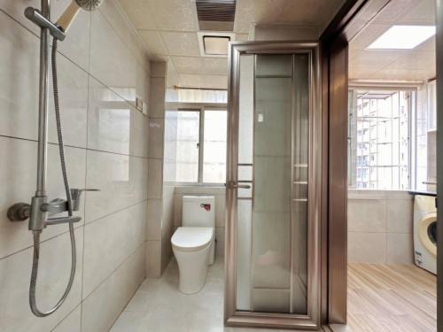 a bathroom with a toilet and a glass shower stall at Ek民宿 in Beihai