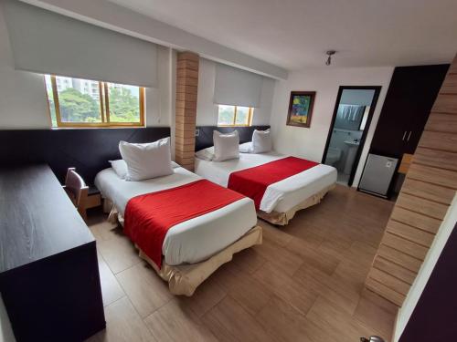 a hotel room with two beds with red sheets at Hotel León Dorado in Bucaramanga