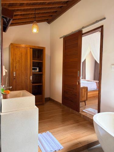 a bathroom with a tub and a bedroom at Wana Ayu Jelijih Villas by Dhananjaya Hospitality in Tampaksiring