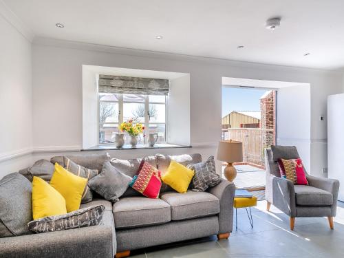 a living room with a gray couch with colorful pillows at The Stables - Uk49089 in Crediton