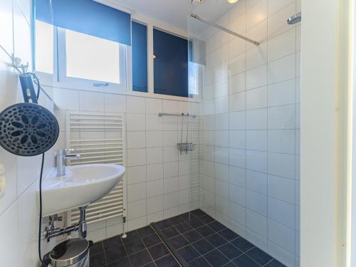 a white bathroom with a sink and a window at Coastal Family Escape with Enclosed Garden in Renesse