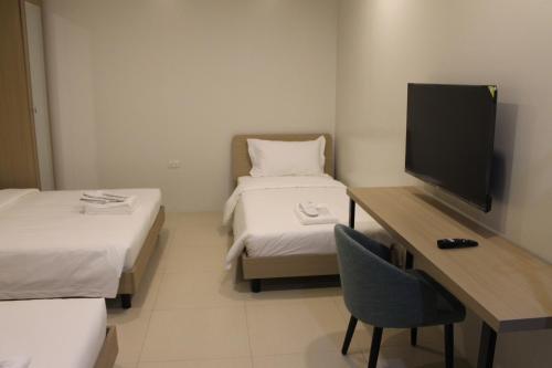 a room with two beds and a desk with a television at The Perch Hostel in Olongapo