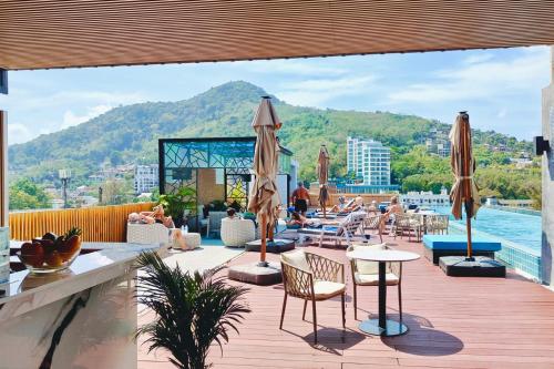 a patio with tables and chairs and a view of the water at Ratana Platinum Resort Kamala in Kamala Beach