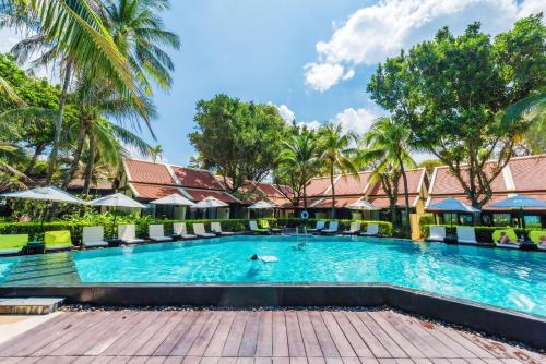 a swimming pool at a resort with palm trees at Impiana Beach Front Resort Patong, Phuket in Patong Beach