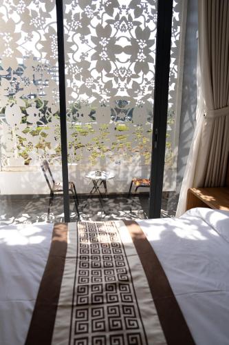 a bedroom with a bed and a window with a curtain at The Healing Luxury Hotel in Buon Ma Thuot