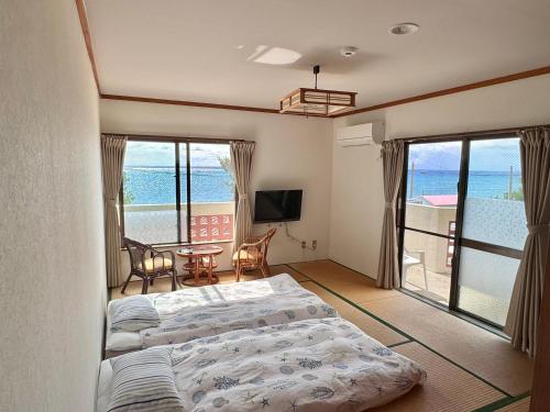 two beds in a room with a view of the ocean at ビーチサイドペンションみーばる in Nanjo
