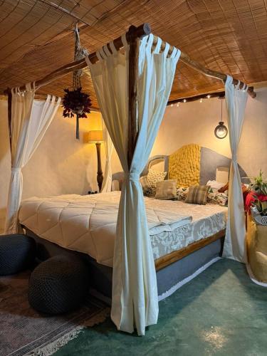 a bedroom with a canopy bed with curtains at The Cob House in Chauntrā