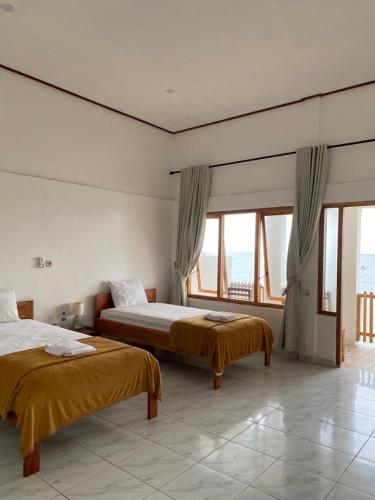 two beds in a room with large windows at Villa Redemptorist in Weetebula