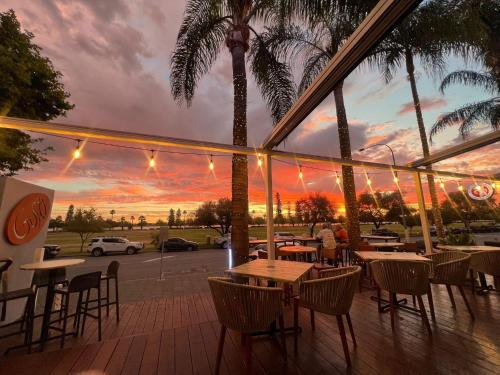 a restaurant with tables and chairs and a sunset at Crowne Plaza Perth by IHG in Perth