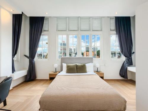 a bedroom with a large bed in front of windows at The White House - Serviced Residences by Cove & Belle Living in Singapore