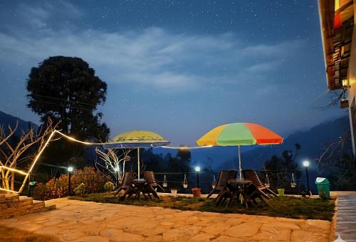 two tables and chairs with umbrellas at night at A Home Above the Clouds Riturain Mukteshwar in Mukteshwar