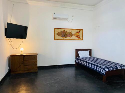 a bedroom with a bed and a dresser and a television at Sri Villa in Dickwella