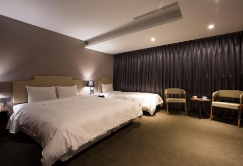a hotel room with two beds and two chairs at Noble Hotel in Taipei