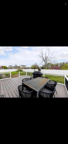 a wooden deck with a picnic table and chairs at The Carneys Point Cottage in Friendship Station
