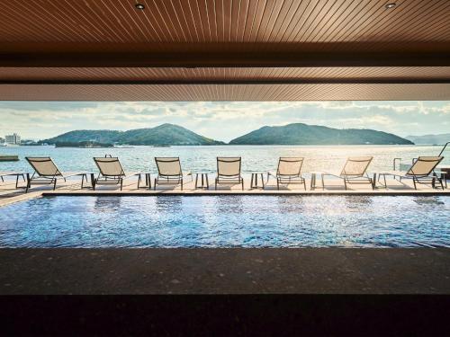 a row of chairs sitting next to the water at edit x seven SETOUCHI SHODOSHIMA in Shodoshima