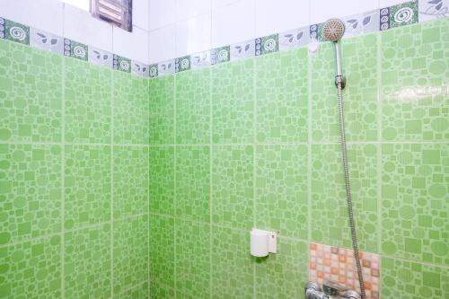 a green bathroom with a shower with green tiles at RedDoorz near RSUD Kebumen 2 in Wanasari