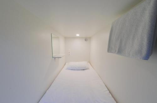 Cette petite chambre blanche dispose d'un lit sur le mur. dans l'établissement Capsule Hotel InterQUBE Bolshaya Polyanka, à Moscou