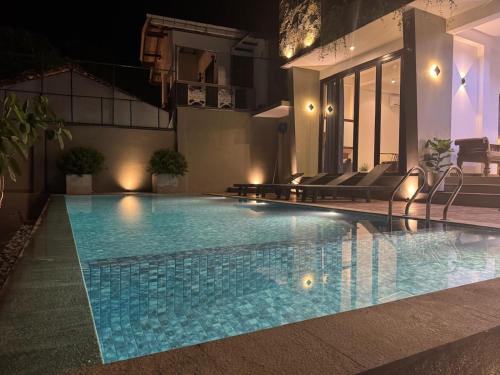 a swimming pool at night with chairs around it at Luma Malee Resort in Dickwella