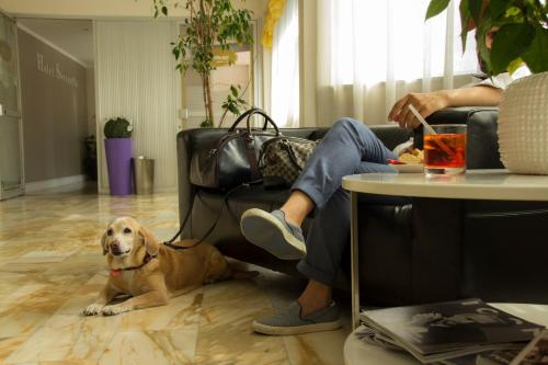 a person sitting on a couch with a dog laying on the floor at Hotel Ristorante Sbranetta in Rozzano