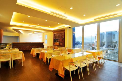 a dining room with yellow tables and chairs and windows at JinShan Sakura Bay Hot Spring Hotel in Jinshan