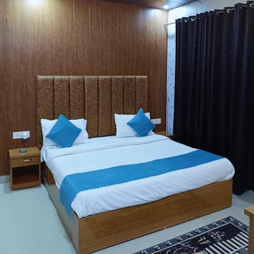 a bedroom with a large bed with blue pillows at Heavens Hotel in Agra