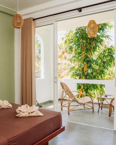 a bedroom with a bed and a chair and a window at Lost Paradise Sri Lanka in Mirissa