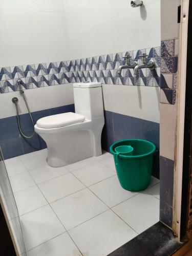 a bathroom with a toilet and a green bucket at Lagoon lake view in Kollam