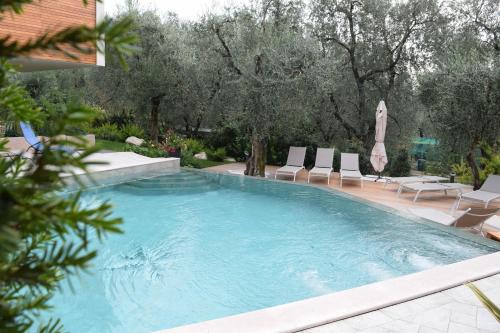 a large swimming pool with chairs and umbrellas at "CASABANA" - relax tutto l'anno - giardino - piscina Top in Malcesine
