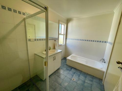 a bathroom with a shower and a sink and a tub at Bayview Beach House Apartment No 1 in Kingscote