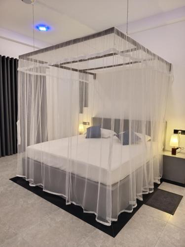 a bedroom with a canopy bed with white drapes at The BLISS Mihiripenna in Talpe