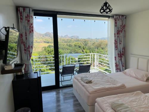a bedroom with two beds and a balcony with a view at พิงภู ไทรโยค กาญจนบุรี in Sai Yok