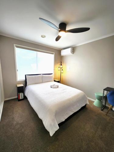 a bedroom with a white bed with a ceiling fan at Private Room 2- Affordable Luxury in Craigieburn