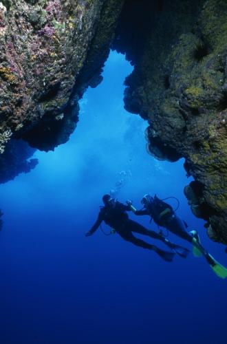 two people swimming in the water near a cave at Heva Eco Lodge in Hanga Roa