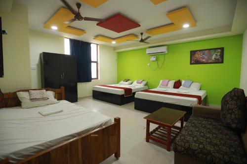 a room with two beds and a couch and a chair at Hotel Madurai Comforts in Madurai