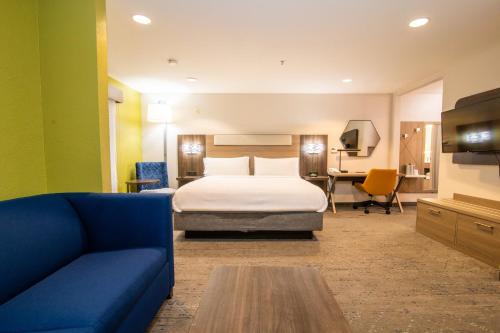 a hotel room with a bed and a couch at Holiday Inn Express & Suites College Station by IHG in College Station
