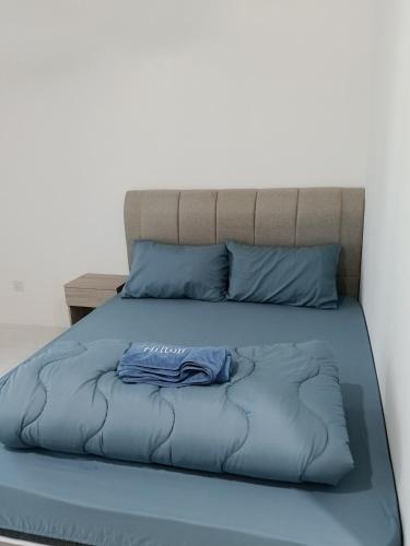 a bed with a blue comforter and blue pillows at D'Tarbiyyah Homestay in Labu
