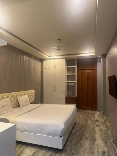 a bedroom with a white bed and a wooden door at Barkah inn in Kannur