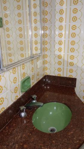 a green sink in a bathroom with a mirror at Hostel da Duda II in Itanhaém