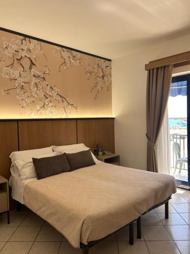 a bedroom with a bed with a painting on the wall at Hotel Al Faro in Licata
