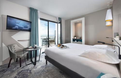 杜阿爾訥內的住宿－Hôtel Valdys Thalasso & Spa - la Baie，酒店客房设有一张大床和一张桌子。