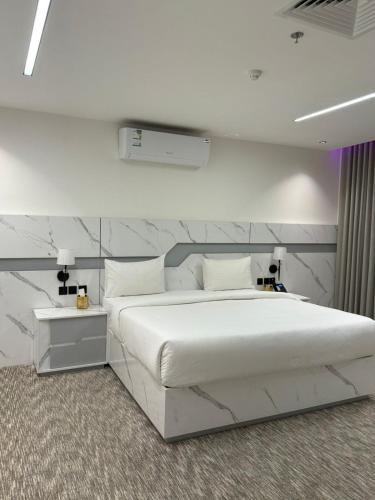 a bedroom with a large white bed and a wall at شقق تارا الفندقية in Najran
